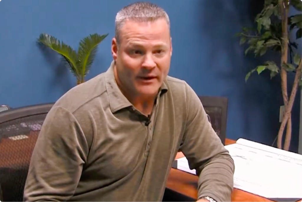 Man wearing a green polo shirt sits in an office.