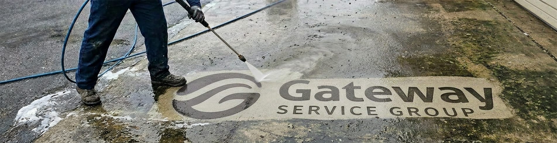 A person using a pressure washer to clean a wet floor with the Gateway Service Group logo.